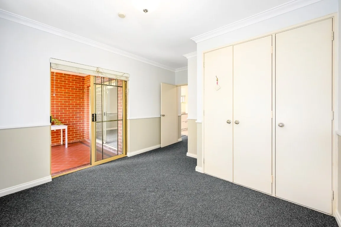 Before photo of an empty carpeted room before being virtually staged as a bedroom.